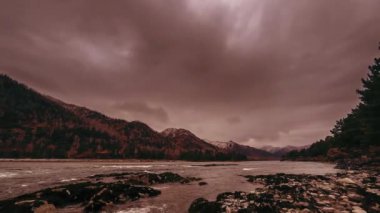 Dağ ormanı yakınlarındaki bir nehrin hızlandırılmış görüntüsü. Büyük kayalar ve hızlı bulutlar hareket ediyor..