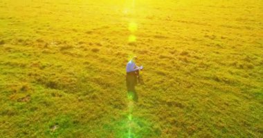 UHD 4k havadan görünümü. Defter pad ile yeşil çim sahasında oturan işadamı üzerinde düşük yörünge uçuş