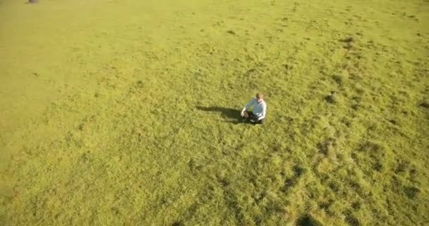 UHD 4k pandangan udara. Penerbangan orbital rendah di atas pengusaha duduk di rumput hijau dengan notebook pad di lapangan — Stok Video