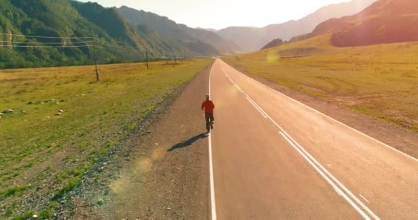 Vlucht van de lage hoogte achter van sportieve man op perfecte asfaltweg — Stockvideo