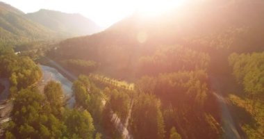 Güneşli yaz sabahında taze dağ nehri ve çayır üzerinde uçuşun ortasında. Aşağıdaki kırsal toprak yol.