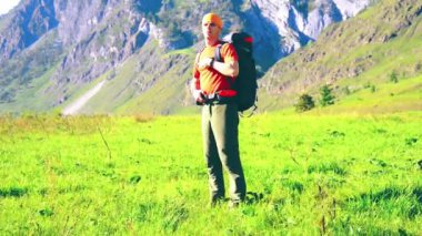 Sırt çantası ile yeşil dağ çayır üzerinde yürüyen adam hiking. Yaz spor ve eğlence kavramı.