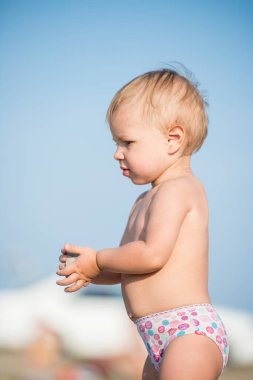 Şirin Bebek denize yakın kum plajındaki oyuncaklar ile oynama.