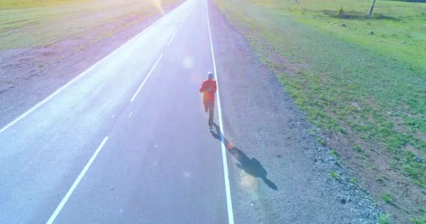 完璧なアスファルト道路でスポーティな男の前で低高度飛行 — ストック動画
