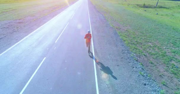 Vol à basse altitude devant un sportif sur une route asphaltée parfaite — Video