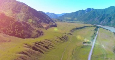 Güneşli yaz sabahında havadan kırsal dağ yolu ve çayır. Asfalt karayolu ve nehir.