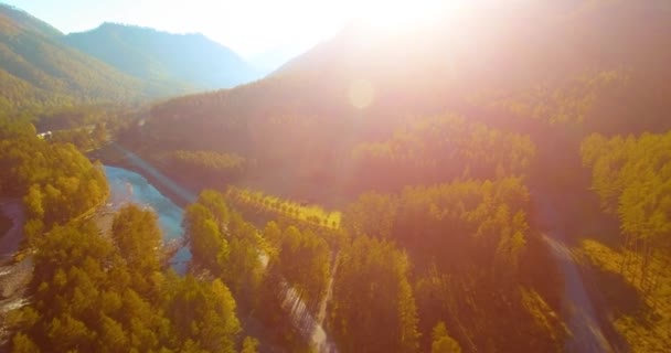 Vôo a meio do ar sobre o rio e o prado frescos da montanha na manhã ensolarada do verão. Estrada de terra rural abaixo. — Vídeo de Stock