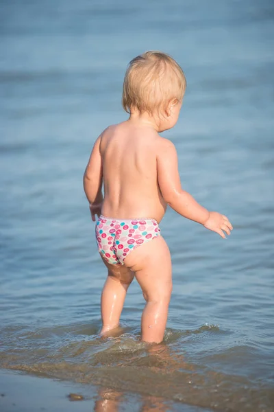 Carino bambino che gioca sulla spiaggia di sabbia e in acqua di mare . — Foto Stock