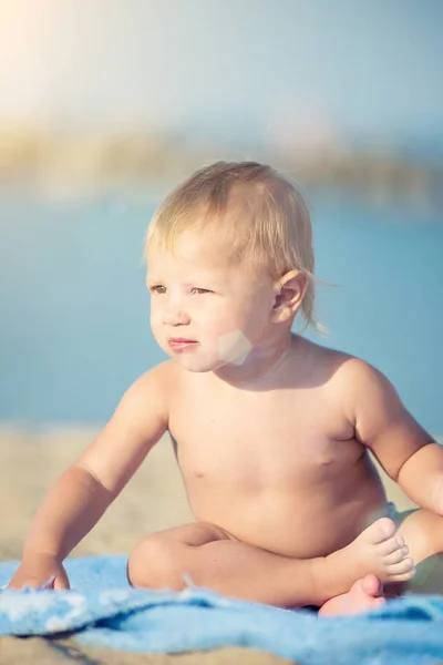 Lindo bebé jugando con juguetes en la playa de arena cerca del mar . — Foto de Stock