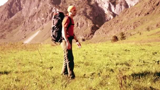 Senderismo hombre caminando en el prado de montaña verde con mochila. Verano deporte y recreación concepto . — Vídeos de Stock