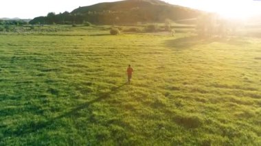 Mükemmel yeşil çayır üzerinde uçan bir sporcu. Dağda gün batımı