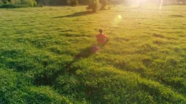 Vol radial à basse altitude au-dessus du yoga sportif homme à l'herbe verte parfaite. Coucher de soleil en montagne. — Video