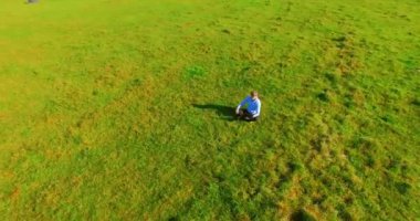 UHD 4k havadan görünümü. Defter pad ile yeşil çim sahasında oturan işadamı üzerinde düşük yörünge uçuş