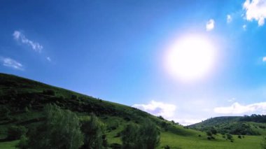 Yazın 4K UHD dağ çayırı zaman dilimi. Bulutlar, ağaçlar, yeşil çimenler ve güneş ışınları hareketi.