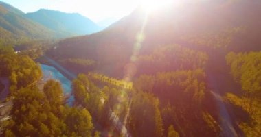 Güneşli yaz sabahında taze dağ nehri ve çayır üzerinde uçuşun ortasında. Aşağıdaki kırsal toprak yol.
