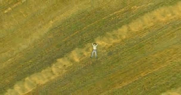 Vista aérea. Vuelo en movimiento vertical sobre el hombre acostado en el campo de trigo amarillo — Vídeos de Stock