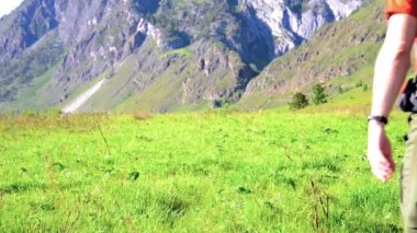 Sırt çantası ile yeşil dağ çayır üzerinde yürüyen adam hiking. Yaz spor ve eğlence kavramı.