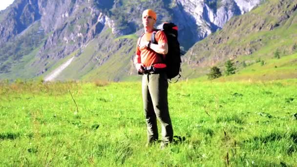 Pěší turistika muž na zelené horské louky s batohem. Letní sportovní a rekreační koncepce. — Stock video