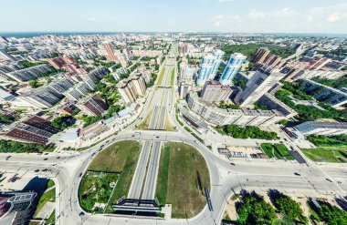 Kesişen yollar, evler, binalar, parklar, otoparklar, köprüler olan havacılık şehri manzarası. Helikopter insansız hava aracı atışı. Geniş Panoramik resim.