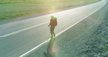 Asfalt yolda yürüyen otostopçu turist üzerinden uçuş. Yaz günü büyük bir kırsal vadi. Sırt çantalı gezgin..