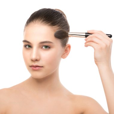 Temiz yüzü ile genç esmer kadın. Kız mükemmel cilt kozmetik fırça uygulamak. Beyaz izole.