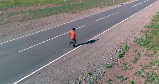 Voo de baixa altitude na frente do homem desportivo na estrada de asfalto perfeito — Vídeo de Stock