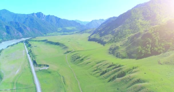 Luftlinie ländliche Bergstraße und Wiese an einem sonnigen Sommermorgen. Asphaltstraße und Fluss. — Stockvideo