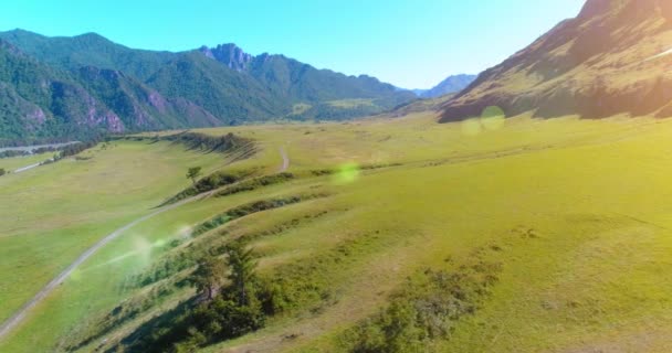 Camino de montaña rural aéreo y prado en la soleada mañana de verano. Autopista del asfalto y río. — Vídeo de stock