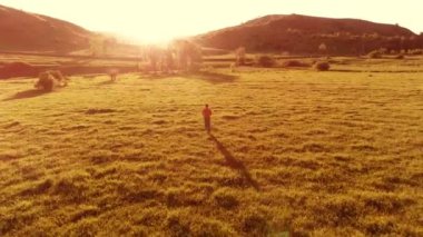 Mükemmel yeşil çayır üzerinde uçan bir sporcu. Dağda gün batımı