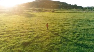 Mükemmel yeşil çayır üzerinde uçan bir sporcu. Dağda gün batımı