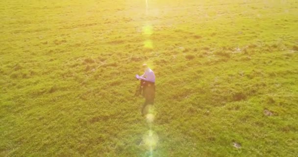 UHD 4k vue aérienne. Vol orbital bas au-dessus de l'homme d'affaires assis sur l'herbe verte avec bloc-notes au champ — Video