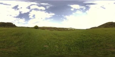360 VR 'lık güzel bir dağ çayırı zaman dilimi. Yaz ya da sonbahar zamanında. Bulutlar, yeşil çimenler ve güneş ışınları.