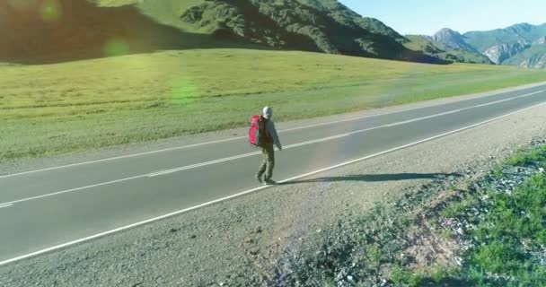 Flug über Tramper Touristen zu Fuß auf asphaltierter Straße. Riesiges ländliches Tal an Sommertagen. Rucksackwanderer. — Stockvideo