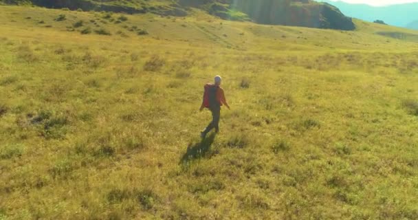 Lot nad plecakiem turysta spacerujący po zielonym polu górskim. Ogromna wiejska dolina w letni dzień. — Wideo stockowe