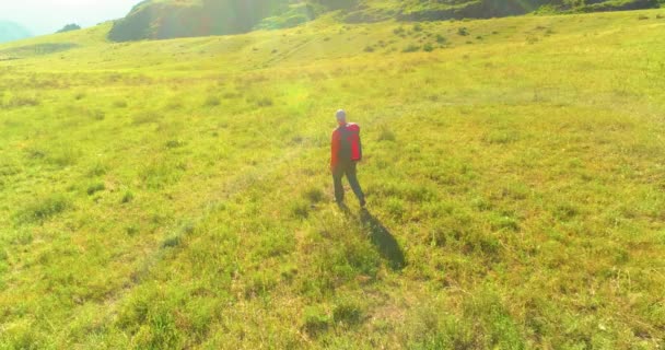 Terbang di atas Backpack hiking turis berjalan melintasi lapangan gunung hijau. Besar lembah pedesaan pada hari musim panas. — Stok Video