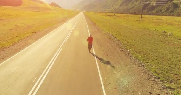 Політ на низькій висоті перед спортивним чоловіком на ідеальній асфальтній дорозі — стокове відео