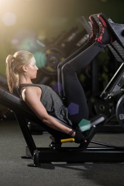 Bacaklar için ağırlıklar basın makine kullanan sportif kadın. Spor salonu.