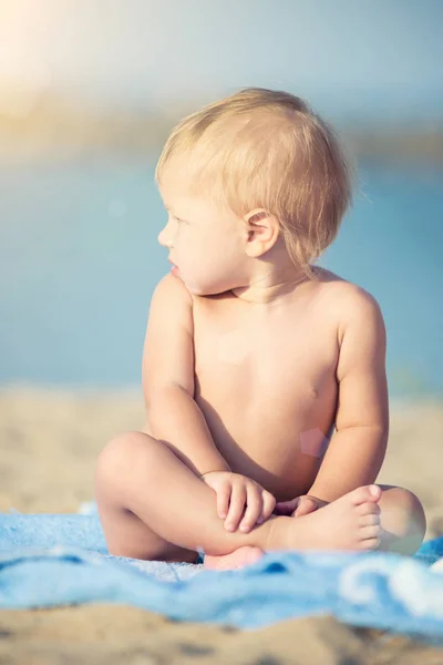 Lindo bebé jugando con juguetes en la playa de arena cerca del mar . —  Fotos de Stock