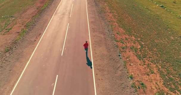 Uhd 鸟瞰图 在新的沥青路面上的运动男子低空飞行 日出在山上 绿色的草地和地平线上的太阳光线 水平运动 — 图库视频影像