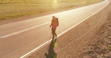 Asfalt yolda yürüyen otostopçu turist üzerinden uçuş. Yaz günü büyük bir kırsal vadi. Sırt çantalı gezgin..