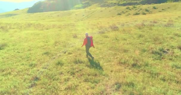 Terbang di atas Backpack hiking turis berjalan melintasi lapangan gunung hijau. Besar lembah pedesaan pada hari musim panas. — Stok Video