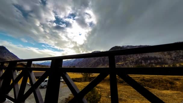 Timelapse van houten hek op hoog terras bij berglandschap met wolken. Horizontale schuifbeweging — Stockvideo