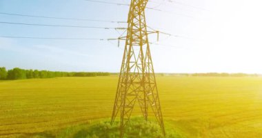 Yüksek voltajlı elektrik kulesi ve yeşil ve sarı alandaki elektrik hatları yakınında dikey hareket.