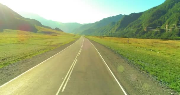 Tiefflug über Bergstraße und Wiese bei sonnigem Sommermorgen. — Stockvideo