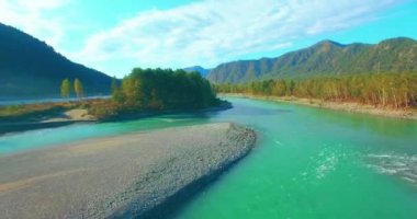 4k UHD hava görüntüsü. Güneşli yaz sabahında taze soğuk dağ nehri üzerinde alçak uçuş. Horisont 'ta yeşil ağaçlar ve güneş ışınları