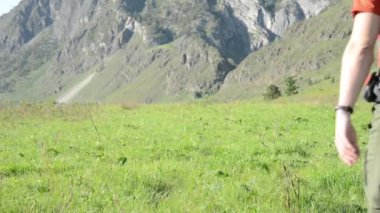 Sırt çantası ile yeşil dağ çayır üzerinde yürüyen adam hiking. Yaz spor ve eğlence kavramı.