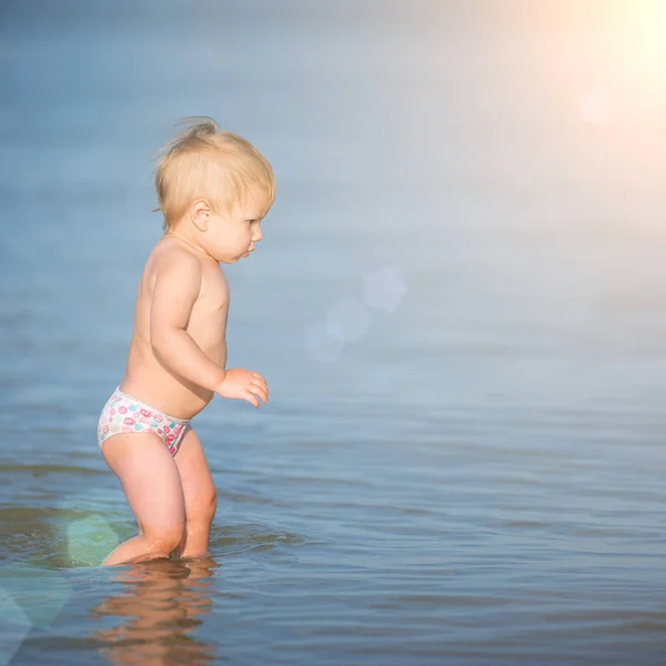 Bébé mignon jouant sur la plage de sable et dans l'eau de mer . — Photo