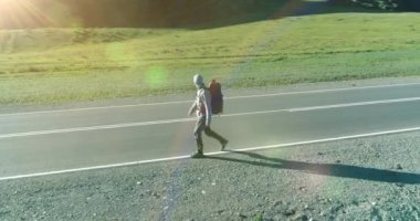 Asfalt yolda yürüyen otostopçu turist üzerinden uçuş. Yaz günü büyük bir kırsal vadi. Sırt çantalı gezgin..