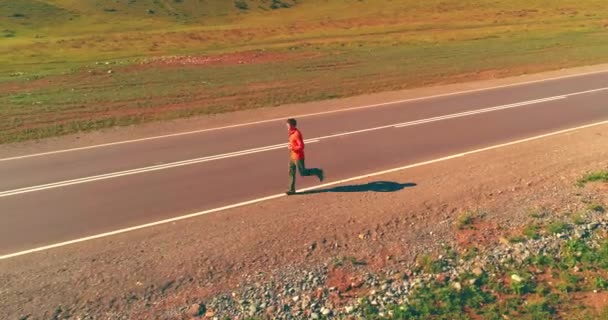 Voo de baixa altitude na frente do homem desportivo na estrada de asfalto perfeito — Vídeo de Stock