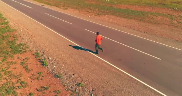 Voo de baixa altitude na frente do homem desportivo na estrada de asfalto perfeito — Vídeo de Stock